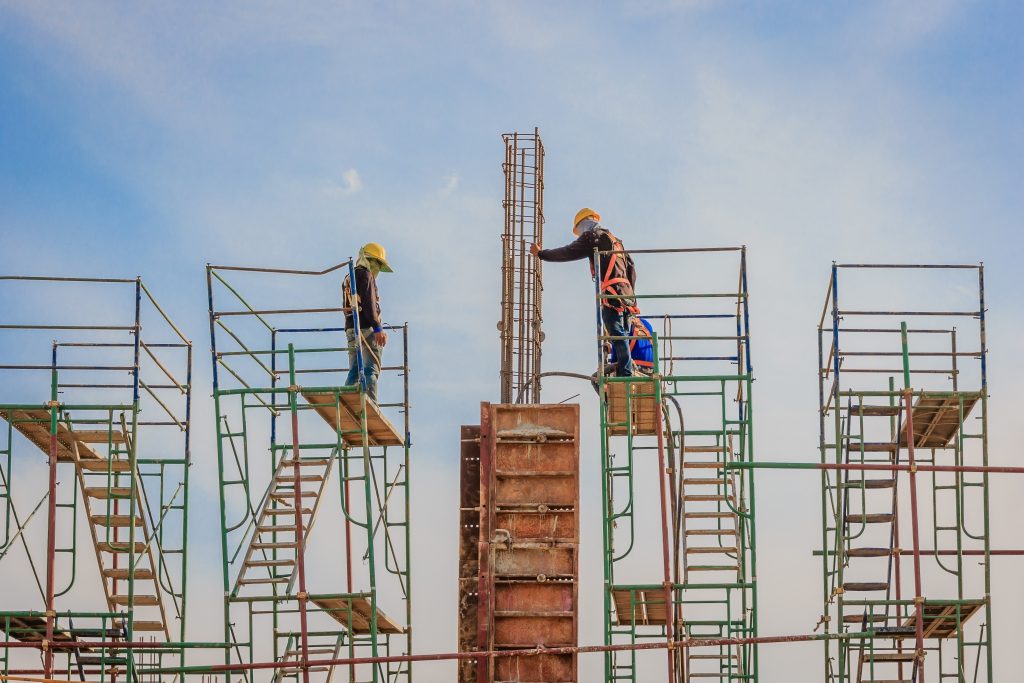 Construction workers working on scaffolding at a high level.